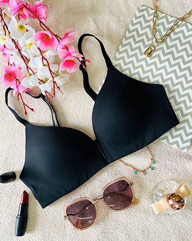 Black lingerie flat lay styled with pink cherry blossoms and jewelry, fashion product photography